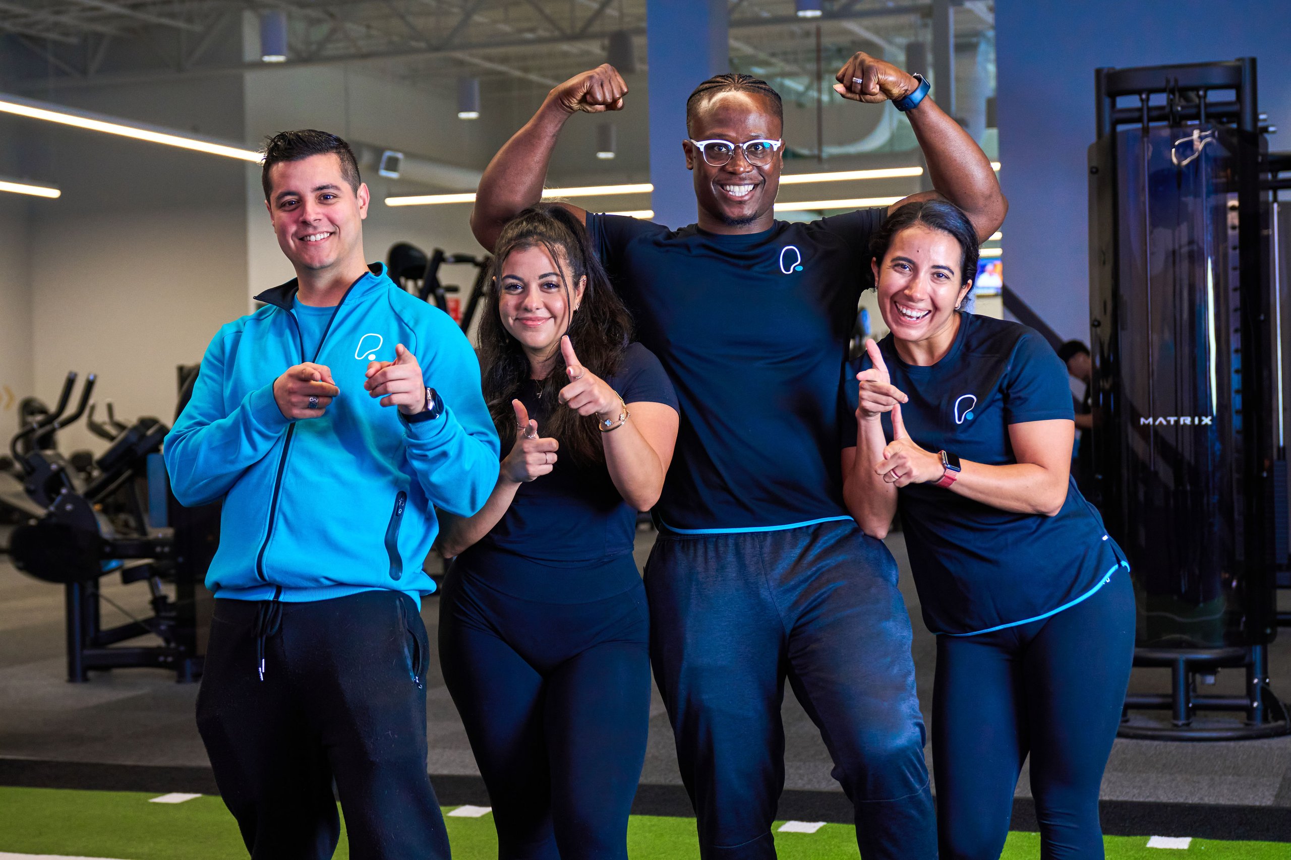 Group of people in gym, pointing, and smiling.