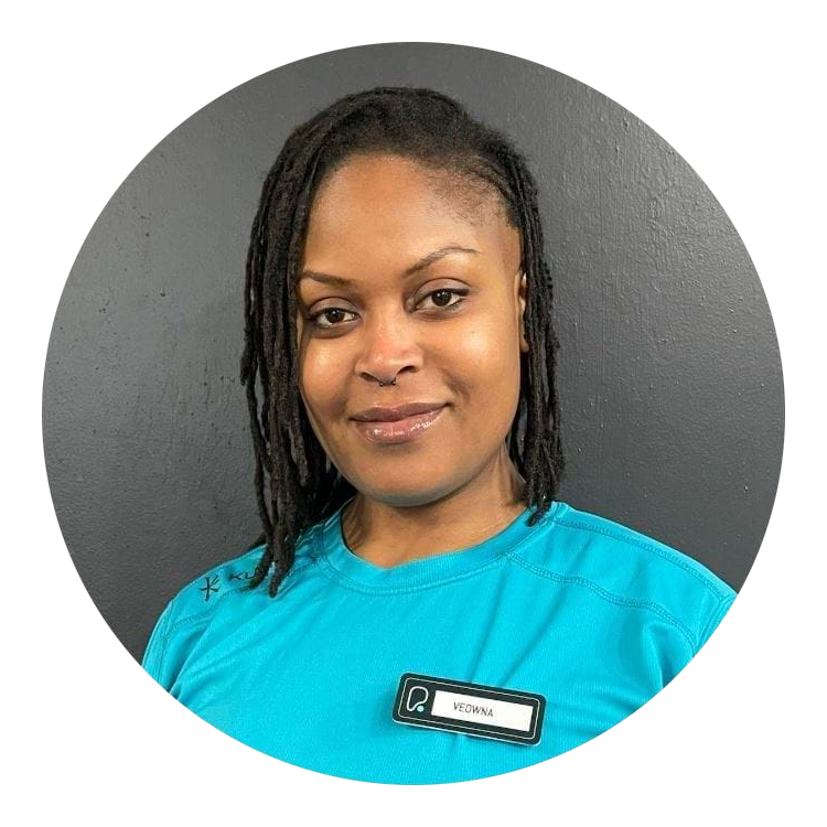 A woman with locs wearing a bright blue shirt and a name tag that reads Veowna.